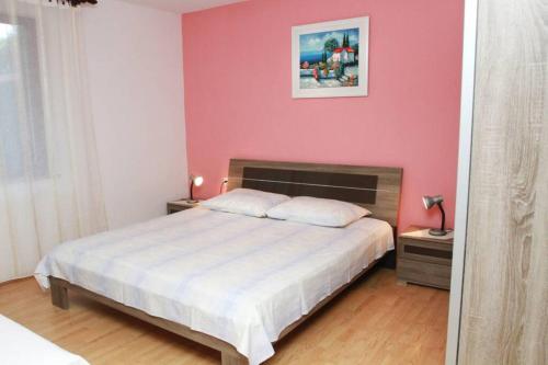 um quarto com uma cama branca e uma parede rosa em Apartment Bareta em Trogir