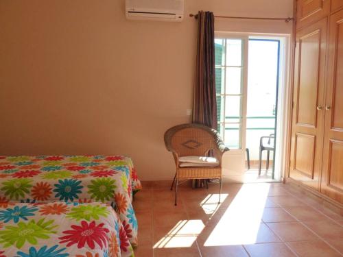 a bedroom with a bed and a chair and a window at 2 bedrooms house at Vila Nova de Cacela 300 m away from the beach with enclosed garden and wifi in Vila Nova De Cacela