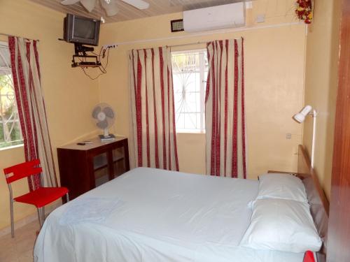 - une chambre avec un lit blanc et une chaise rouge dans l'établissement 2 bedrooms appartement with shared pool furnished balcony and wifi at Flic en Flac, à Flic-en-Flac