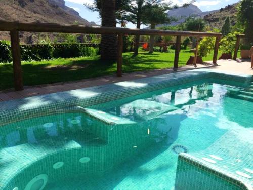 a swimming pool with blue water in a resort at One bedroom villa with enclosed garden and wifi at San Bartolome de Tirajana in San Bartolomé