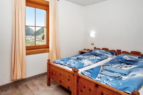 een slaapkamer met een bed met blauwe lakens en een raam bij 4 bedrooms apartement at Livigno 50 m away from the slopes with balcony and wifi in Livigno