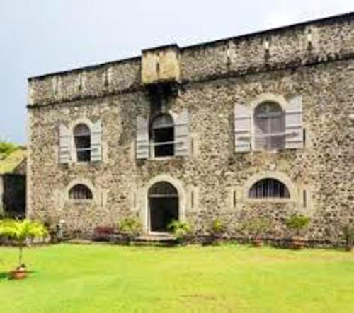 a large brick building with windows and a grass yard at Appartement panoramique Bouillante in Bouillante
