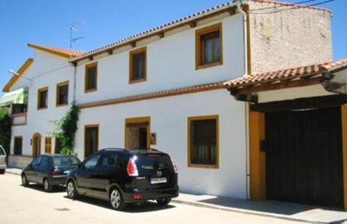 two cars parked in front of a white house at Mountain House in Ivanrey in Ciudad-Rodrigo
