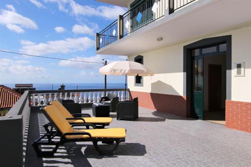 a group of chairs and an umbrella on a balcony at Elegant House in Calheta, Sea View in Calheta
