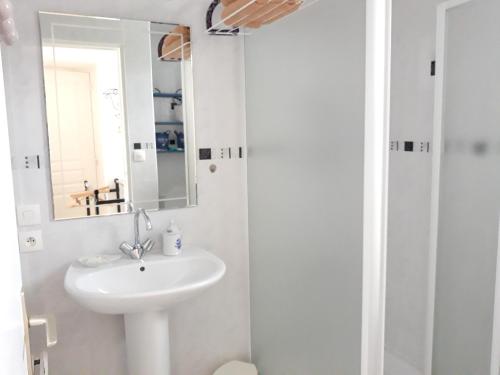 La salle de bains blanche est pourvue d'un lavabo et d'un miroir. dans l'établissement Appartement d'une chambre avec jardin clos et wifi a Sainte Marie du Mont a 1 km de la plage, à Sainte-Marie-du-Mont