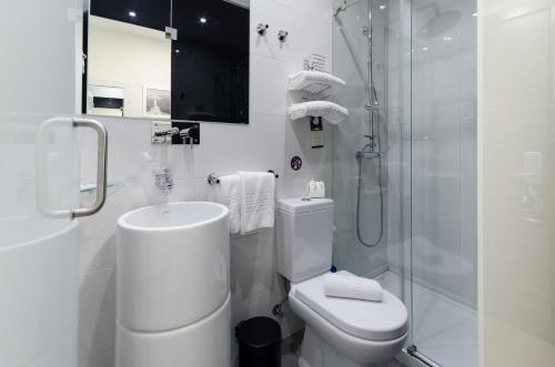 a white bathroom with a toilet and a shower at Hotel Borges Chiado in Lisbon