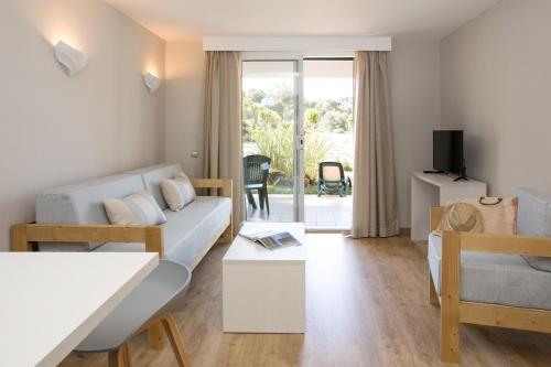 ein Wohnzimmer mit einem Sofa und einem Tisch in der Unterkunft Minura Cala Galdana & Apartamentos d'Aljandar in Cala Galdana