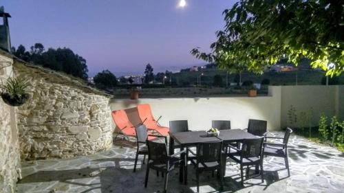 a patio with a table and chairs and a stone wall at Casa Rubal in Foz
