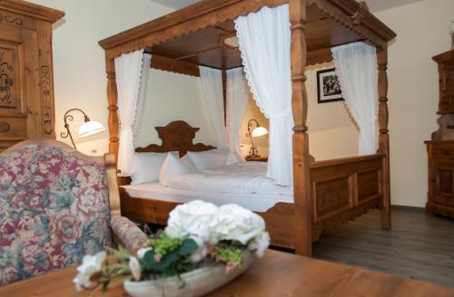 een slaapkamer met een hemelbed en een tafel bij Landhotel Altes Pfarrhaus in Bilzingsleben