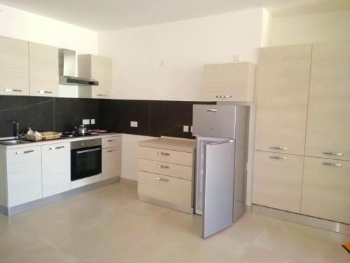 a kitchen with white cabinets and a stainless steel refrigerator at Bright apartment with sea view in Għajnsielem - 120 sqm in Għajnsielem