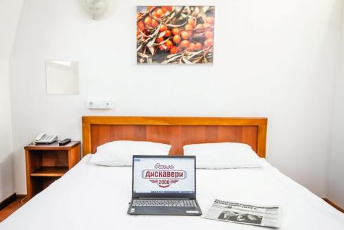 ノヴォシビルスクにあるDiscovery Hotelの- ノートパソコン(ベッドの上に座る)