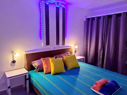 a bedroom with a bed with colorful pillows on it at Maison de charme à Sainte-Rose avec piscine partagée in Sainte-Rose