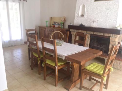 una sala da pranzo con tavolo, sedie e camino di Villa avec jardin à Poussan avec piscine privée ouverte toute l'année a Poussan