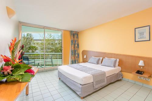a hotel room with a bed and a balcony at Zenitude Hôtel Résidences Le Salako in Le Gosier