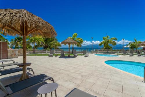 a resort with a swimming pool with chairs and umbrellas at Zenitude Hôtel Résidences Le Salako in Le Gosier