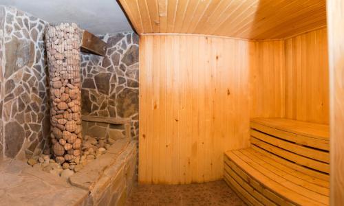 una sauna con pared de piedra y paredes de madera en Cottage Gutsulia, en Yaremche