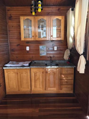 a kitchen with a sink and wooden cabinets at RANCHO COSTEIRO AGROTURSIMO E BALNEARIO E PESQUEIRO in Pôrto Xavier