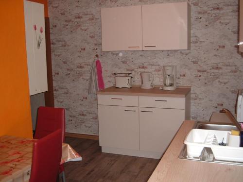 ヴェルニゲローデにあるFerienwohnungen Pookの白いキャビネット、シンク、カウンター付きのキッチン