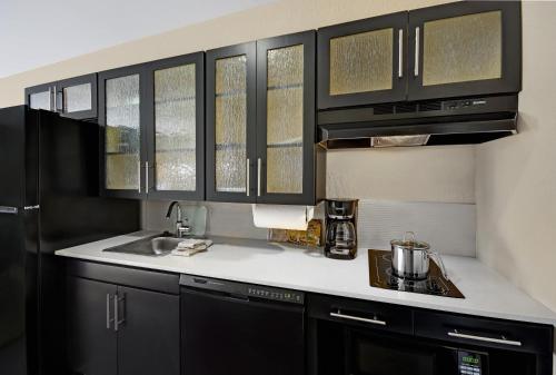 a kitchen with black cabinets and a sink at Candlewood Suites Sumter by IHG in Sumter