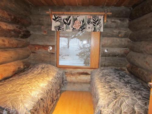 1 dormitorio con 2 camas en una cabaña de madera en Rukakaiku Cottages, en Ruka
