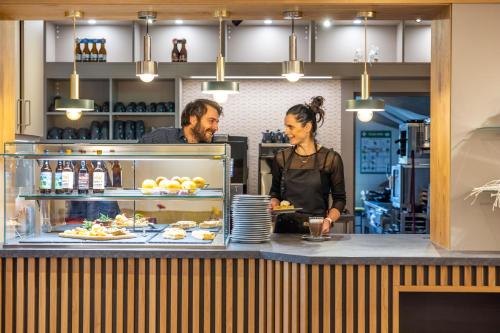 a man and a woman standing behind a counter with food at Pension & Café Abendröte in Kurort Oybin