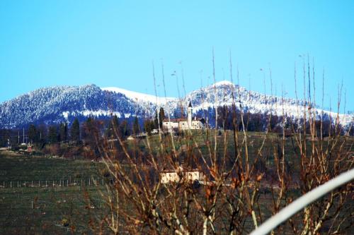 a snow covered mountain with a house in a field at Garage con camere in Pieve di Soligo