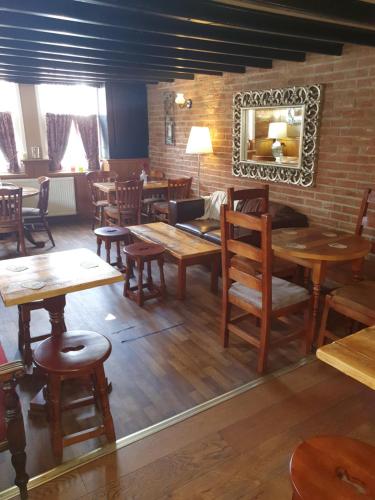 Un restaurante con mesas y sillas de madera y un espejo. en Windmill Bed and Breakfast, en Beverley