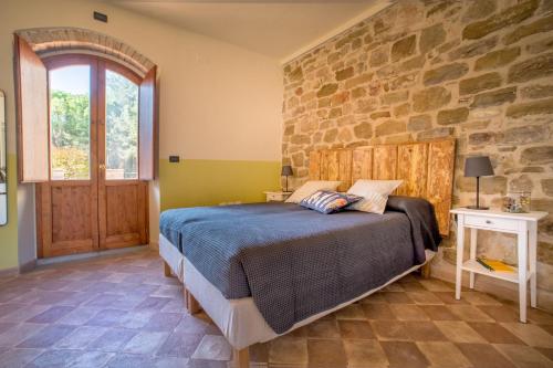 a bedroom with a bed and a stone wall at Torrenova di Assisi Country House in Assisi