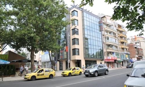 
a car is driving down a street next to tall buildings at Hotel Burgas Free University in Burgas

