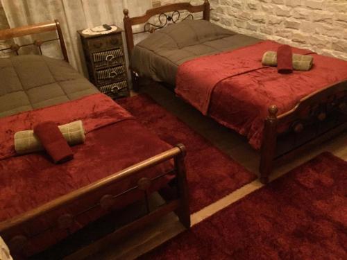 2 bedden met rode dekens in een kamer bij The Love Holiday House in Tris Elies