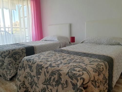 a hotel room with two beds and a window at Apartamento Porticada in Guardamar del Segura