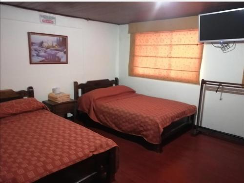 een kamer met 2 bedden en een flatscreen-tv bij Hotel Consuelo in Tunja