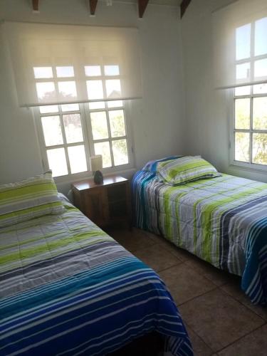 a bedroom with two beds and two windows at Casa Tunquen VIP in Tunquen