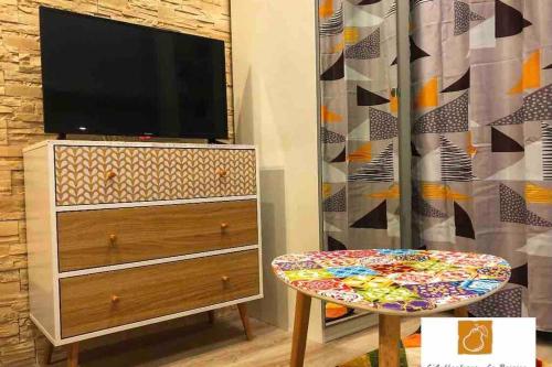 - un salon avec une télévision, une table et une commode dans l'établissement L'Authentique - Le Poirier, à Orléans