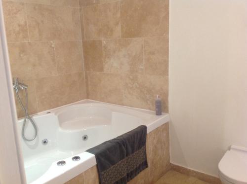 a bathroom with a bath tub and a toilet at A Room in the City - West in Edinburgh