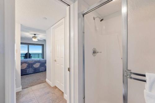 a bathroom with a walk in shower next to a bedroom at Commodore 802 in Panama City Beach