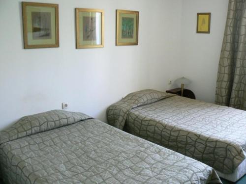 two beds in a hotel room with pictures on the wall at Family Art Hotel Gallery in Pleven