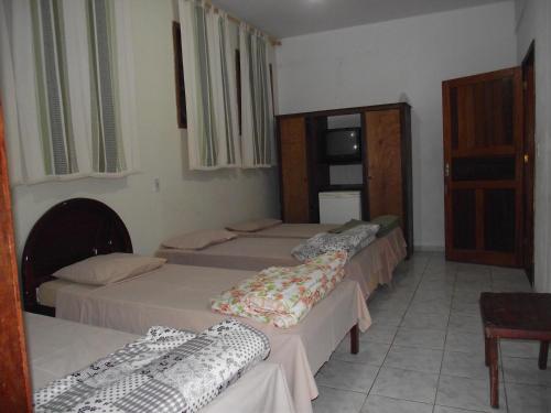 a group of four beds in a room at Hotel Miguel Pereira in Miguel Pereira