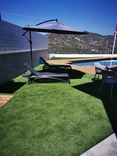 two lawn chairs and an umbrella next to a pool at Maximos Luxury Villa with Pool -BREAKBOOKING-CY in Limassol