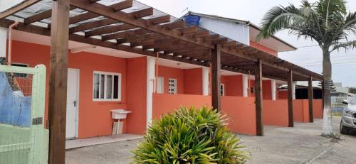a house with an orange wall and a fence at RESIDENCIAL FÁVERO in Capão da Canoa