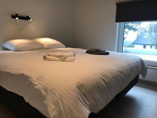 ein Schlafzimmer mit einem Bett mit weißen Laken und einem Fenster in der Unterkunft Villa Charles in Francorchamps