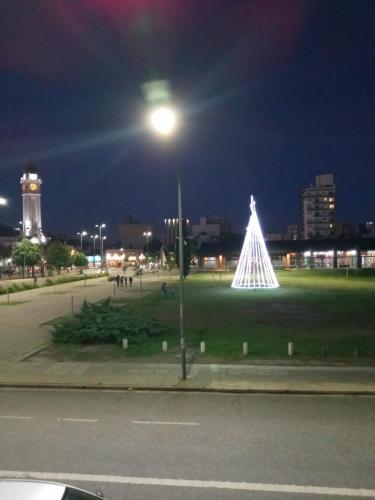 Un arbre de Noël éclairé dans un parc la nuit dans l'établissement Hostel en rosario, à Rosario