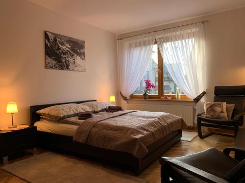 een slaapkamer met een bed, een raam en een stoel bij Apartament Góralka in Zakopane