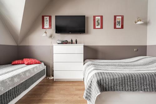 a bedroom with two beds and a tv on the wall at Willa Jaś I Małgosia in Kościelisko