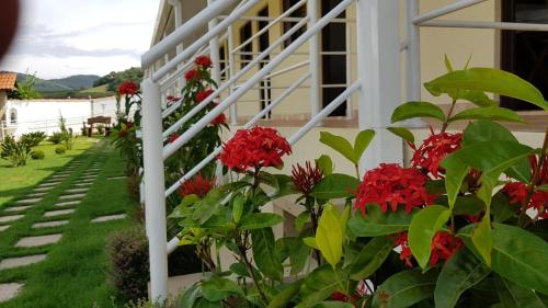 a white railing with red flowers on the side of a house at Pousada Canto dos Canários in Socorro