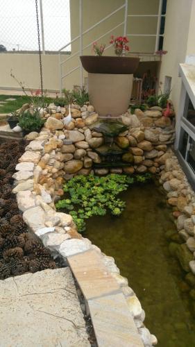 a garden with a pond and a rock wall at Pousada Canto dos Canários in Socorro
