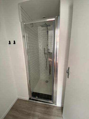 een douche met een glazen deur in de badkamer bij Cosy Flat Carteret - Appartement centre bourg - 4 personnes in Barneville-Carteret