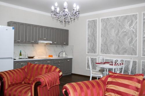 a living room with a couch and a table and a kitchen at Golden Park Hotel in Pavlodar