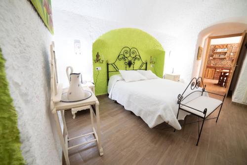 a bedroom with a white bed and a green wall at Cuevas Cortijo Gachas in Guadix