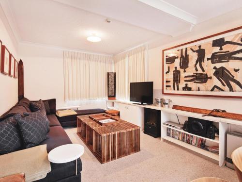 a living room with a couch and a tv at Steamboat 2 bedroom with mountain view and central location in Thredbo